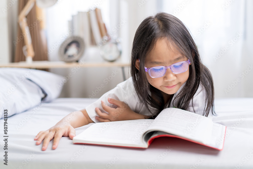 Asian child little girl reading books lying on the bed at home. Asian child little girl reading books lying on the bed at home.