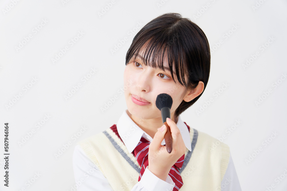 白背景でチークブラシを使う女子高生 白背景でチークブラシを使う女子高生