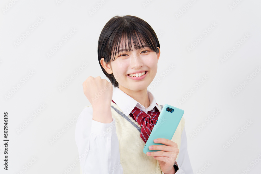 白背景でスマホを持ってガッツポーズをする女子高生 白背景でスマホを持ってガッツポーズをする女子高生