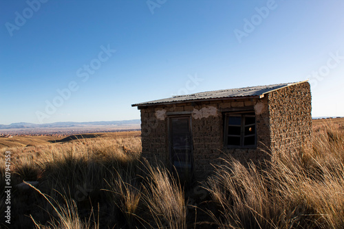 Mud house facade with window and old wooden door, high-rise construction in the Andes. house in the height of Bolivia. dry and cold season. 3600 - 4000 masl photo