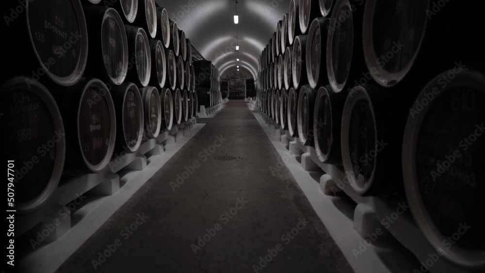 Barrels in warehouse stacked. Wooden oak whiskey, wine or beer barrels sitting in rows inside storage cellar Barrels in warehouse stacked. Wooden oak whiskey, wine or beer barrels sitting in rows inside storage cellar