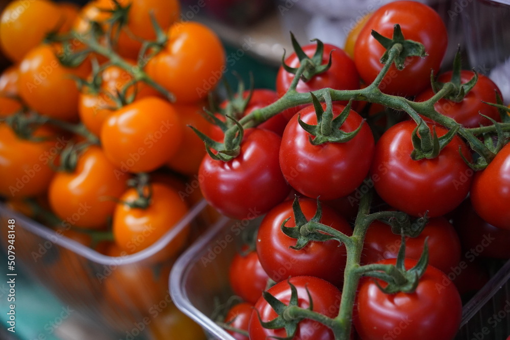 Almaty, Kazakhstan - 03.25.2022 : A variety of tomatoes on a twig lie in containers for sale at the market. Almaty, Kazakhstan - 03.25.2022 : A variety of tomatoes on a twig lie in containers for sale at the market.