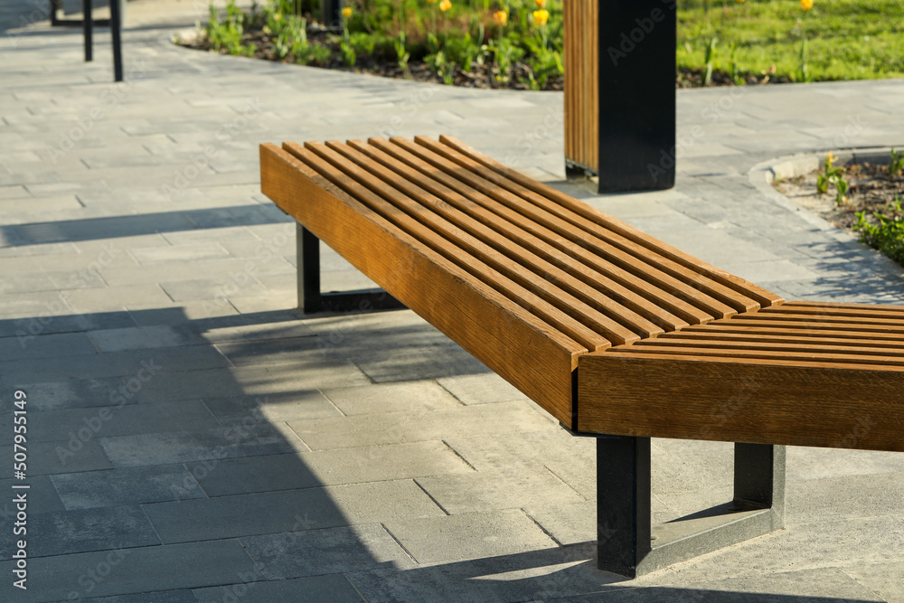 Wooden bench in city park on sunny morning Wooden bench in city park on sunny morning