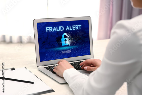 Fraud prevention security system. Woman using laptop at white table, closeup