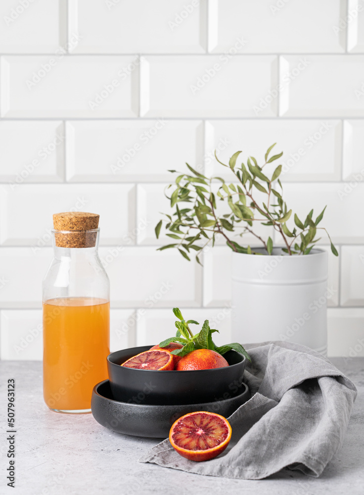 Freshly squeezed orange juice in a bottle on the kitchen table with fresh red oranges on plate. The concept of a healthy drink. Front view and copy space Freshly squeezed orange juice in a bottle on the kitchen table with fresh red oranges on plate. The concept of a healthy drink. Front view and copy space