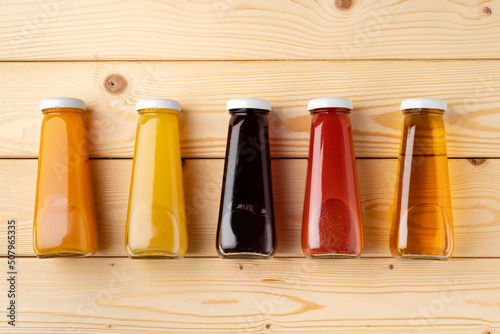 Juice bottles on wooden background flat lay