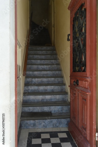 Porte ouverte rouge qui donne sur un escalier qui monte