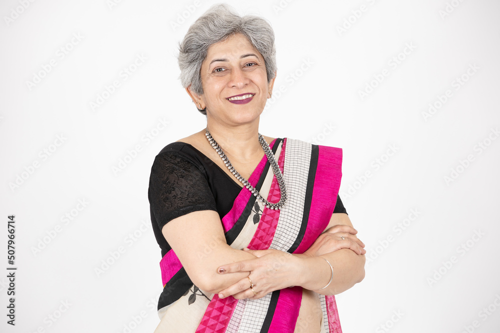 Happy senior indian woman wearing saree standing cross arms