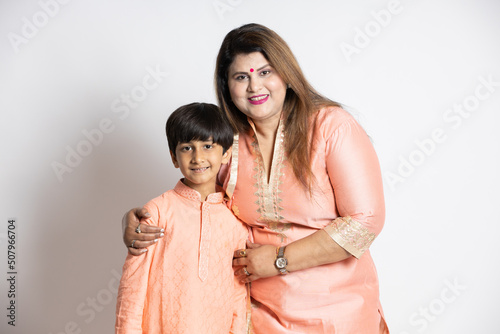 Happy young indian mother with her little son wearing ethnic festive outfit isolated over white background. Smiling asian family. Plus size woman with little child boy.