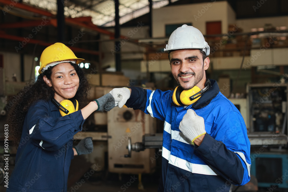 Happy smiling teamwork technician engineer or worker in protective uniform and hardhat make fist bumping celebrate successful together completed deal commitment at heavy industry manufacturing factory Happy smiling teamwork technician engineer or worker in protective uniform and hardhat make fist bumping celebrate successful together completed deal commitment at heavy industry manufacturing factory