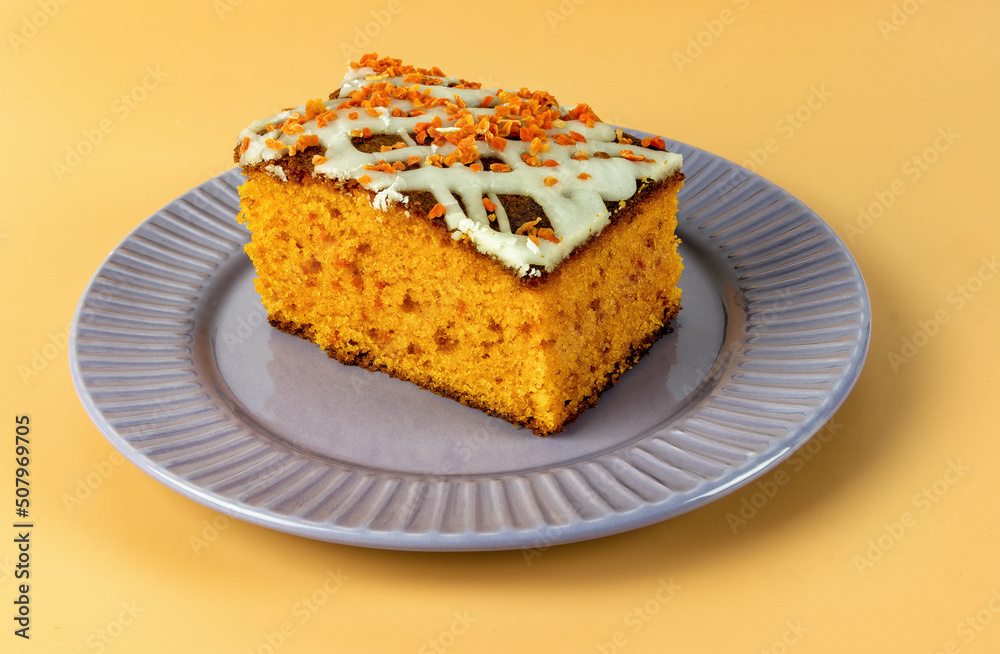 piece of carrot cake with white cream on a yellow background piece of carrot cake with white cream on a yellow background