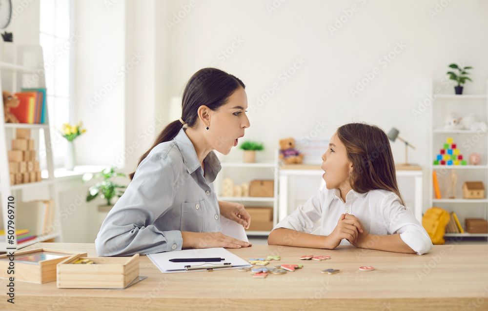 Happy child and female speech therapist, mother or private English tutor doing mouth exercise, working on correct O letter sound, fixing stuttering stammering impediment problem, having fun together Happy child and female speech therapist, mother or private English tutor doing mouth exercise, working on correct O letter sound, fixing stuttering stammering impediment problem, having fun together