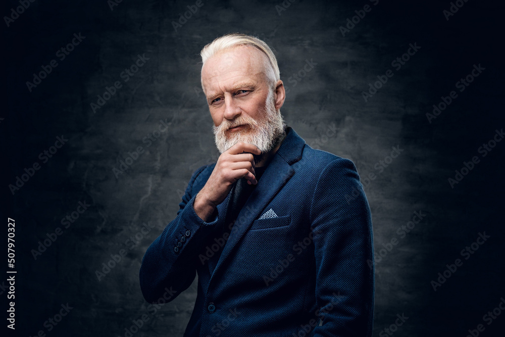 Studio shot of thoughtful senior man with stylish hairstyle dressed in blue suit against dark background. Studio shot of thoughtful senior man with stylish hairstyle dressed in blue suit against dark background.