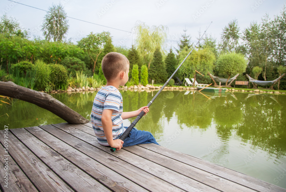 little boy is fishing on the lake, summer day. International Children's Day little boy is fishing on the lake, summer day. International Children's Day