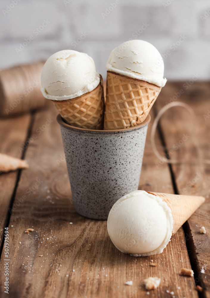 vanilla ice cream with a waffle cone in a ceramic glass on a wooden table vanilla ice cream with a waffle cone in a ceramic glass on a wooden table