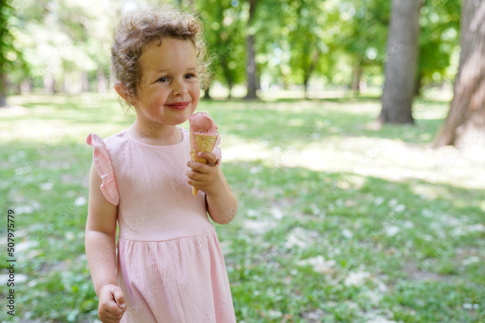 3 years old kid girl in pink dress eating tasty ice cream in the park 3 years old kid girl in pink dress eating tasty ice cream in the park
