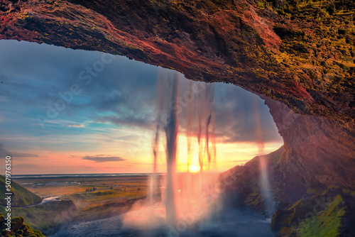 Last sunlight flowing of Seljalandsfoss waterfall, where tourists can walk behind the falling waters. Astonishing summer scene of Iceland, Europe. Beauty of nature concept background.