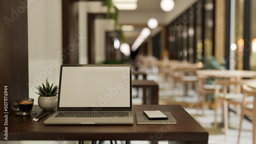 Comfortable workplace with notebook laptop on table over blurred coffee shop or library seating area