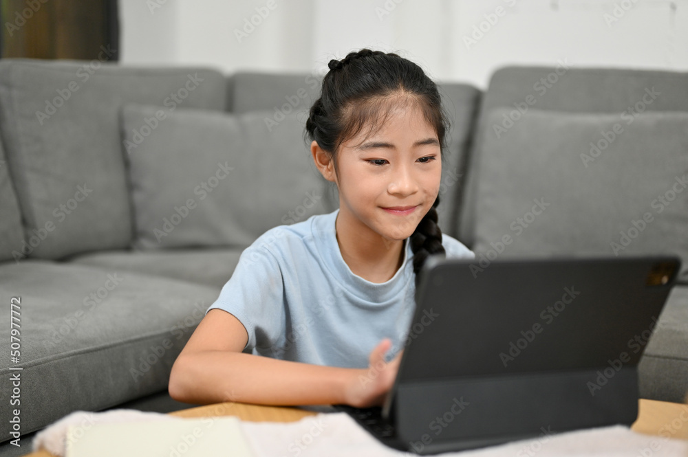 Cute Asian young girl watching something on tablet screen Cute Asian young girl watching something on tablet screen