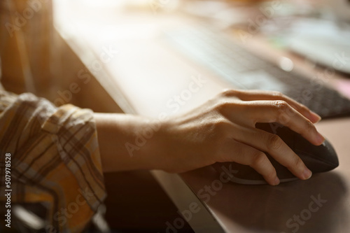 Close-up image, Female hand using a wireless computer mouse at her office desk.