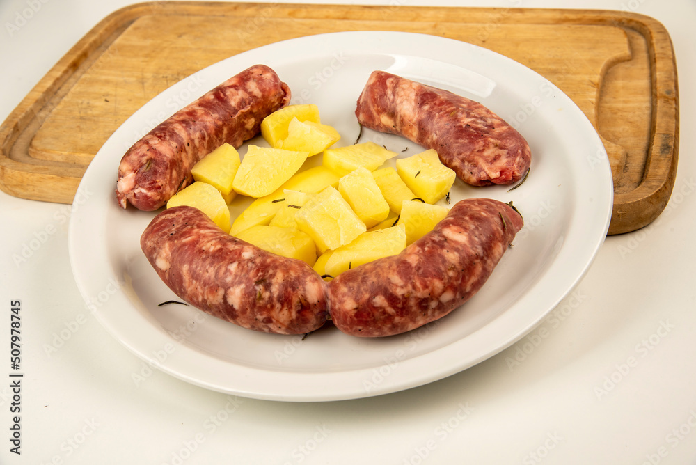 Sausages with fennel with potato garnish on a white plate Sausages with fennel with potato garnish on a white plate