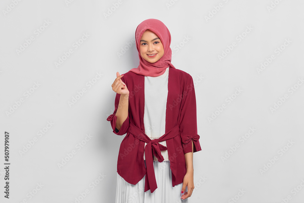 Smiling beautiful Asian woman in casual shirt showing korean heart with two fingers crossed, expresses joy and positivity isolated over white background