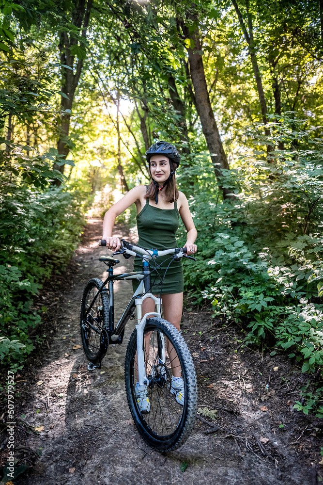 Pretty young slim woman on a bicycle rest after activity in the forest
