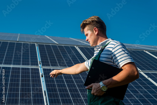 Portrait of worker in protective uniform standing near solar panels