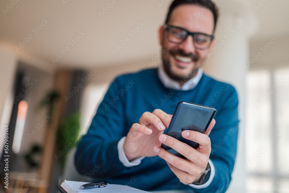Close-up of young businessman text messaging on smart phone at office. Focus on phone and hands. Close-up of young businessman text messaging on smart phone at office. Focus on phone and hands.