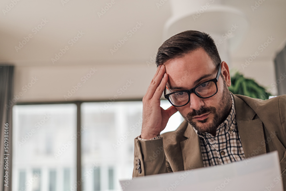 Fototapeta premium Close-up of tensed young professional analyzing document while working at office