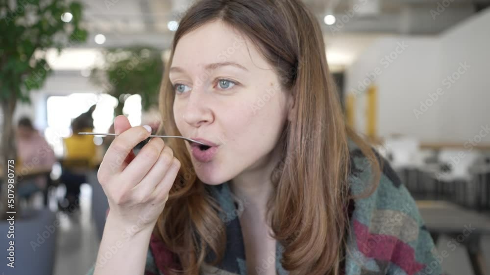 Young woman tastes food and contentedly smiles looking at camera. Female guest enjoys healthy dish with avocado and turkey in restaurant closeup Young woman tastes food and contentedly smiles looking at camera. Female guest enjoys healthy dish with avocado and turkey in restaurant closeup