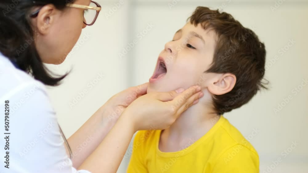medical examination. Pediatrician feels the tonsils in a child with a sore throat and shows his tongue medical examination. Pediatrician feels the tonsils in a child with a sore throat and shows his tongue