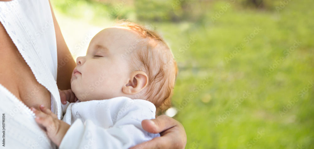 Concept of motherhood. Parenthood. breastfeeding. baby's healthy sleep. mom holds a small sleeping baby in the garden on a summer day Concept of motherhood. Parenthood. breastfeeding. baby's healthy sleep. mom holds a small sleeping baby in the garden on a summer day