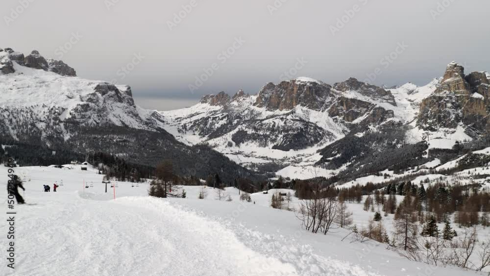 Alpine Skiers Descending a Beautiful Snowy Slope and a view of the Beautiful Surrounding Landscape of the Snow-covered of the Italian alps Dolomites Mountains Alpine Skiers Descending a Beautiful Snowy Slope and a view of the Beautiful Surrounding Landscape of the Snow-covered of the Italian alps Dolomites Mountains