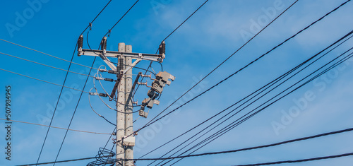 tall electric poles with wires stretching obliquely in a photo frame against a blue sky background