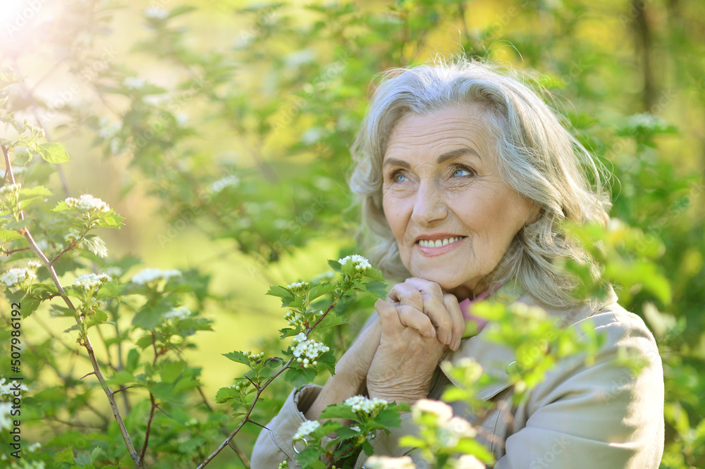 Beautiful senior woman posing near blooming tree Beautiful senior woman posing near blooming tree