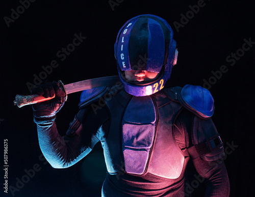 Cyberpunk future concept. Bionic cyborg police officer with short samurai sword stands in dark. Halfman robot looks at camera. Futuristic science fiction scene. photo
