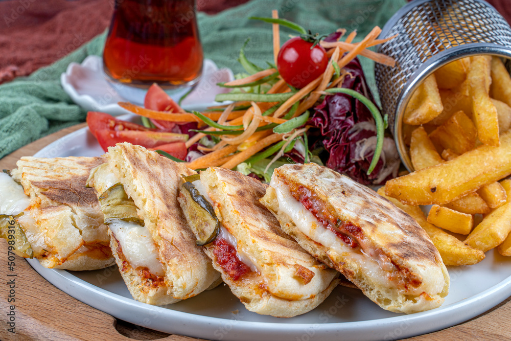Bazlama Toast,Turkish toast flat baked bread called bazlama with Turkish sausage and cheese served with fried patatoes,salad and a glass of tea