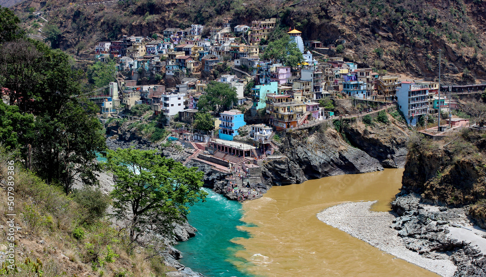 Tributaries or Ganges river meeting and mixing blue and brown waters near a small town on a cliff
