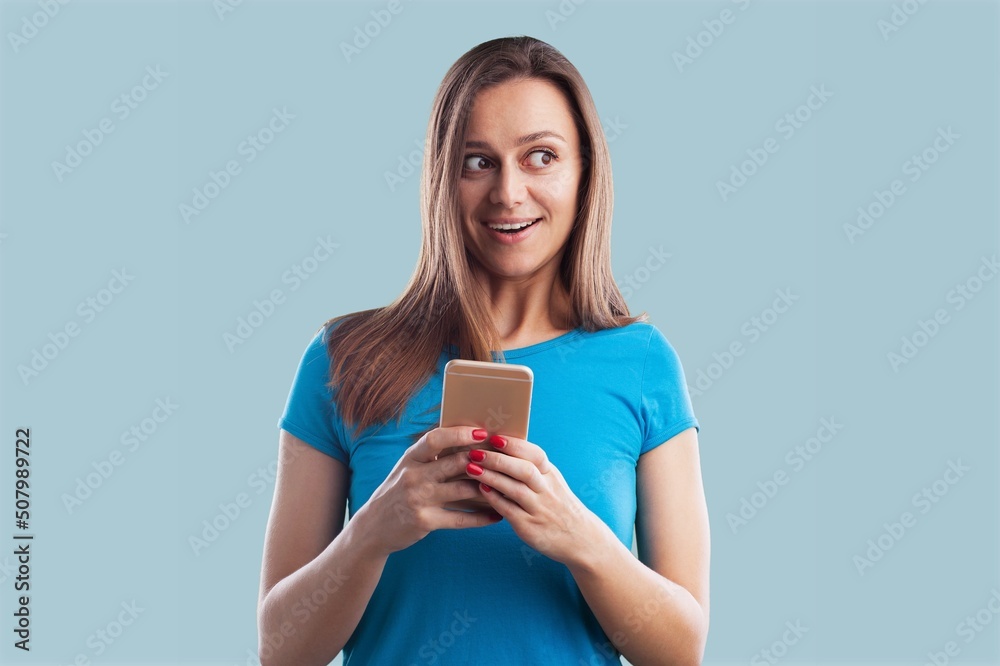 Young smiling happy woman wearing blue shirt hold in hand use mobile phone. Young smiling happy woman wearing blue shirt hold in hand use mobile phone.