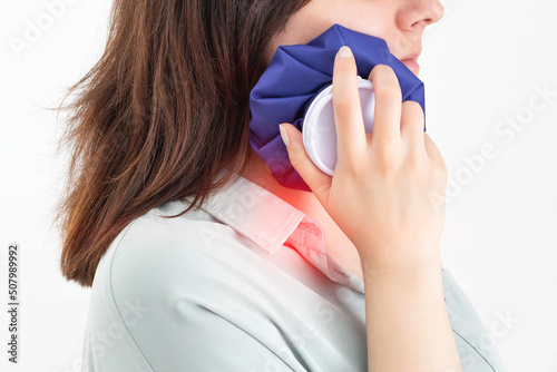 A girl attaches a medical bag with cold to the swelling on her cheek after removing a wisdom tooth. Concept for pain relief and inflammation in dentistry with the help of cold photo