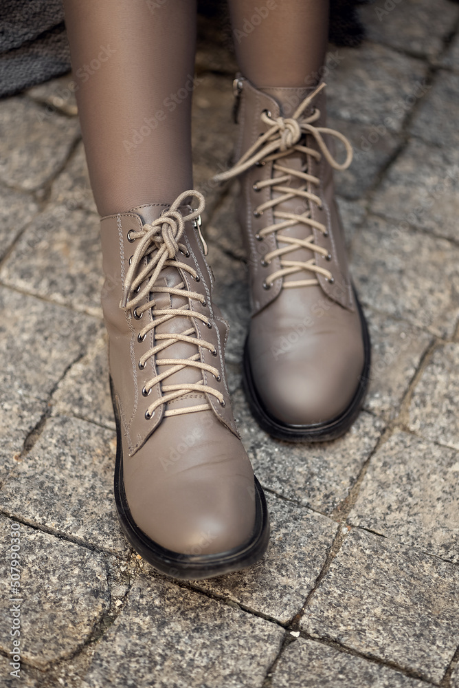 Stylish casual leather boots or shoes on woman legs on cobblestone surface Stylish casual leather boots or shoes on woman legs on cobblestone surface