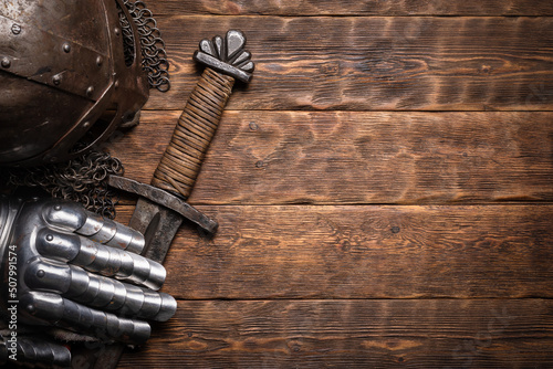 Leinwand Poster Ancient knight sword and armor on the wooden table flat lay background with copy space