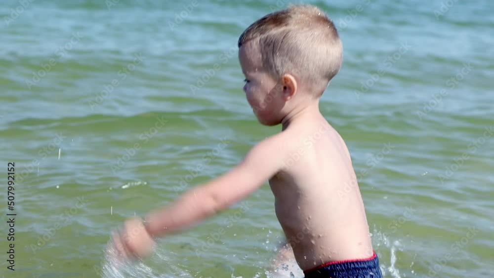 happy caucasian baby kid boy splashing playing in sea ocean water in sunny day. 3 year child having fun in water on summer vacations. healthy lifestyle, learning to swim in salt sea ocean. fun, joy happy caucasian baby kid boy splashing playing in sea ocean water in sunny day. 3 year child having fun in water on summer vacations. healthy lifestyle, learning to swim in salt sea ocean. fun, joy