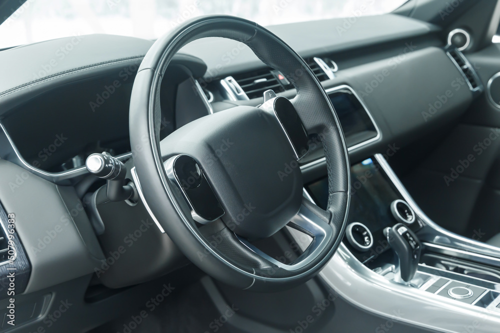 The interior of a modern car in close-up. Car interior - steering wheel, gear shift lever, multi-touch steering wheel, car control display, dashboard. Black leather. A place to copy. Without a label.