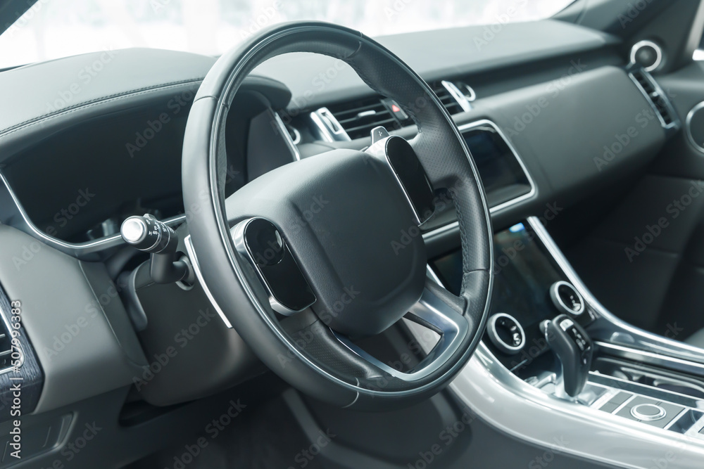 The interior of a modern car in close-up. Car interior - steering wheel, gear shift lever, multi-touch steering wheel, car control display, dashboard. Black leather. A place to copy. Without a label. The interior of a modern car in close-up. Car interior - steering wheel, gear shift lever, multi-touch steering wheel, car control display, dashboard. Black leather. A place to copy. Without a label.
