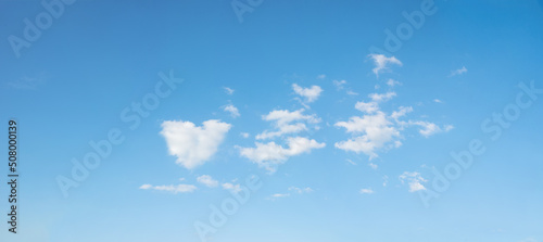 blue sky background with some fluffy clouds, one in a heart shape