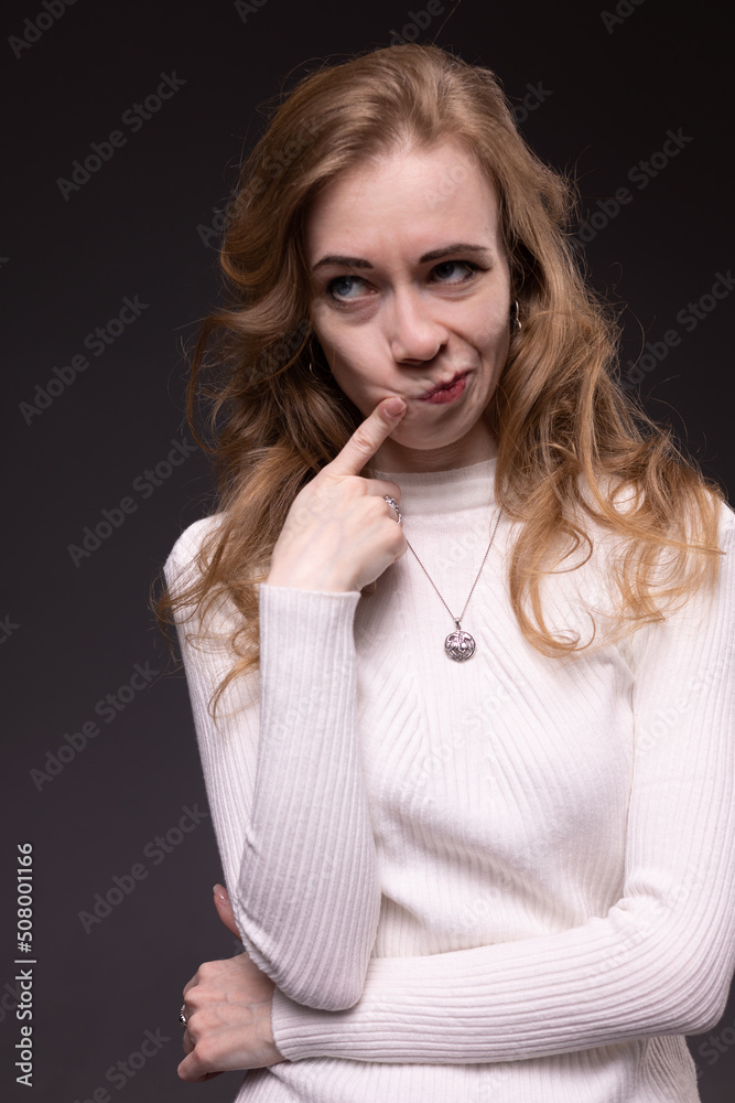 Portrait of playful girl making faces. Mixed emotions on face: fooling, flirting and smiling. Sitting, black background. Portrait of playful girl making faces. Mixed emotions on face: fooling, flirting and smiling. Sitting, black background.