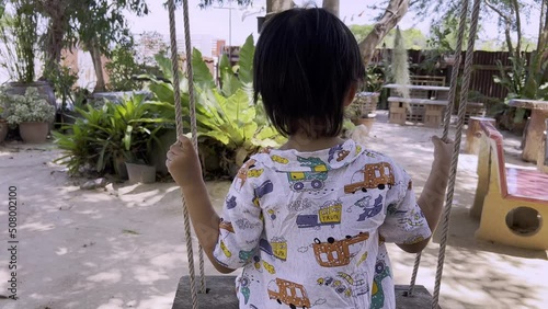 Funny kid boy having fun with rope swing on outdoor playground