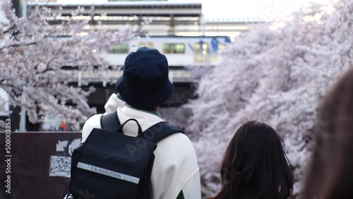 NAKAMEGURO, TOKYO, JAPAN - APRIL 2022 : View of Cherry blossoms at Meguro river and unidentified people enjoying the scenery. Japanese spring season concept video. Slow motion shot. photo